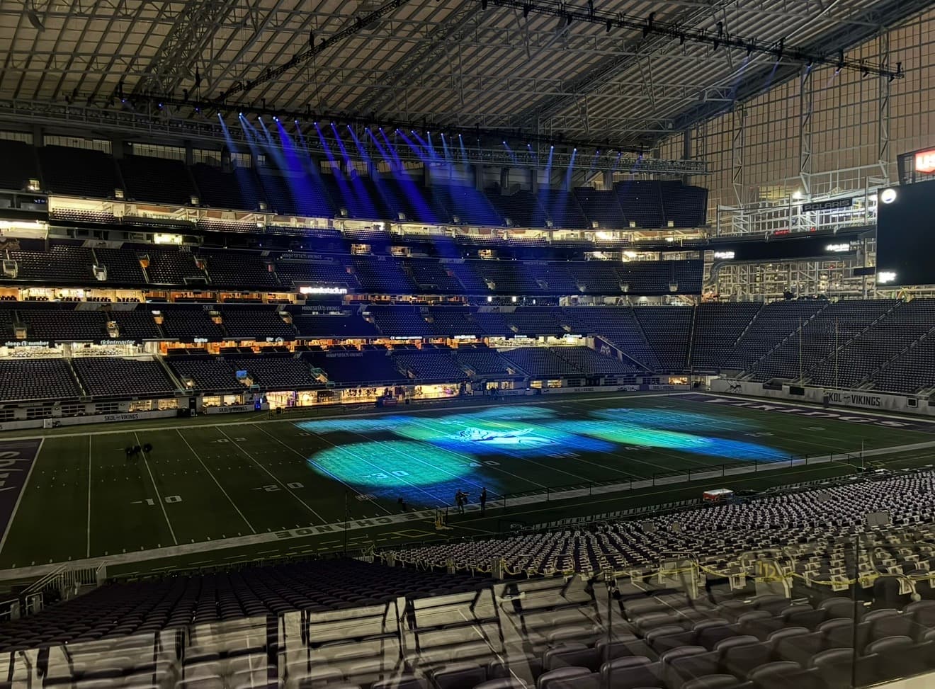 U.S. Bank Stadium during the halftime build — blue stage lighting sweeping the empty bowl and field.